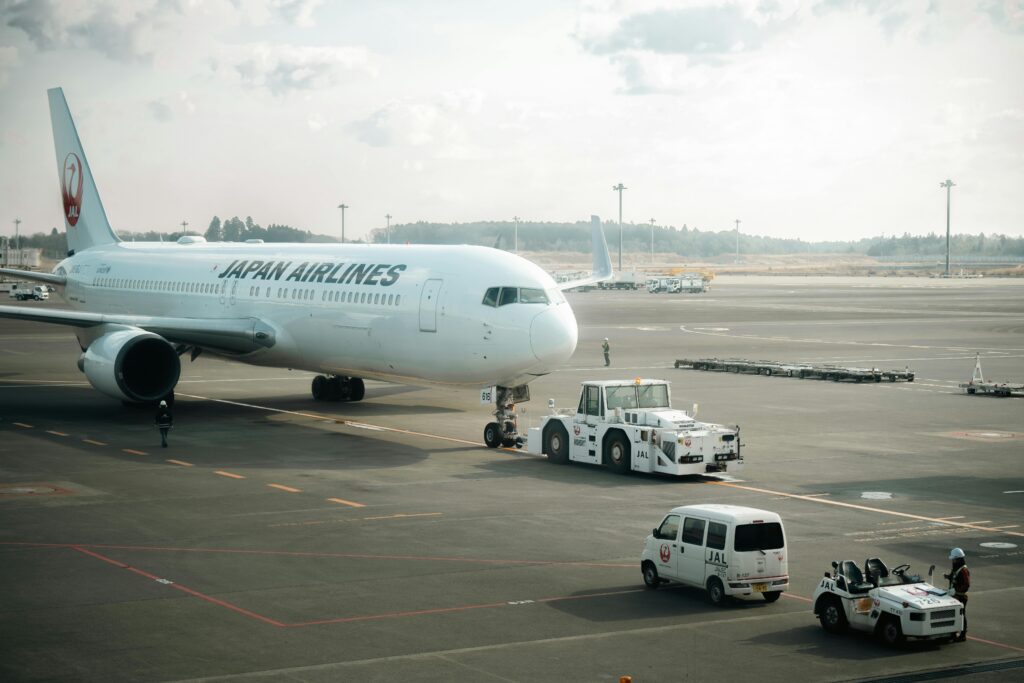 Japan Airlines aircraft stationed on the tarmac in Tokyo with ground crew vehicles.